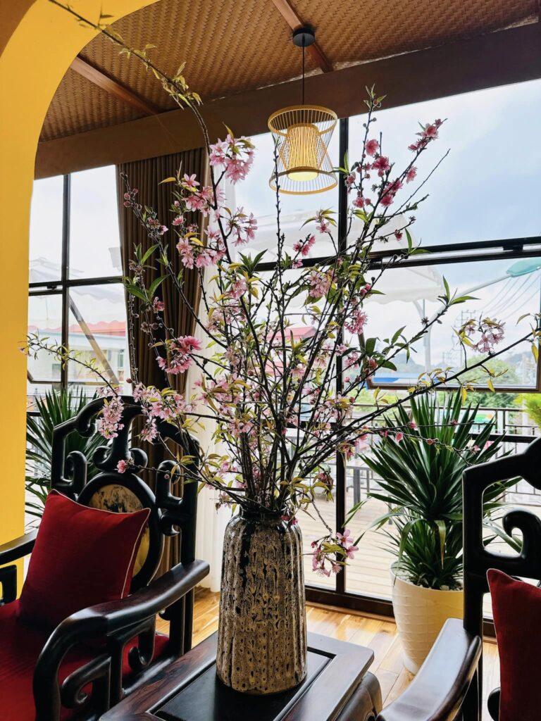 Top 3 Lý Do May Coffee Mộc Châu Chọn Cót Ép Nhân Tạo Cho Trần Nhà 4 Cây hoa đào trang trí đặt giữa không gian quán có trần cót ép nhân tạo và trụ gỗ ốp vân