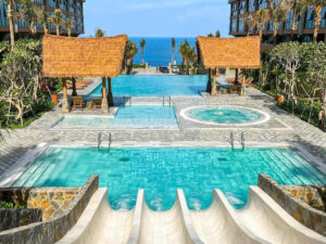 Hồ bơi resort với mái chòi lợp mái lá nhân tạo, hướng nhìn ra biển xanh